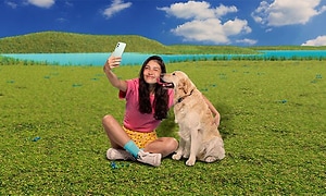 Kvinne som holder OnePlus Nord 2 og tar en selfie sammen med hund