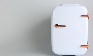 lite, hvitt kjøleskap på lysegrå bakgrunn