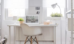 En hvit Acer-laptop på et hvitt bord på et hjemmekontor