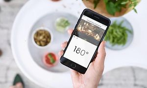 Hånd holder smarttelefon med app som viser smartovn og temperaturen på ovnen på skjermen