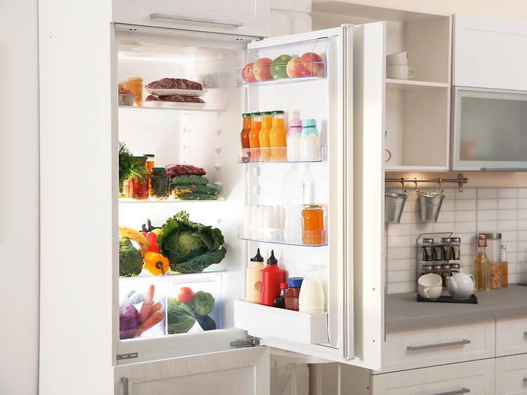 Integrert kjøleskap med åpen dør i et hvitt kjøkken