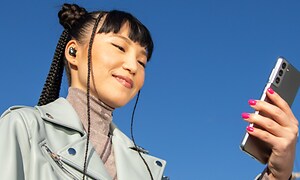 Headphones-Beats-Kvinne med Studio Buds Sound ser på mobi