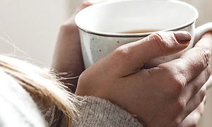 Nærbilde av en kvinnes hender som holder en kopp med te