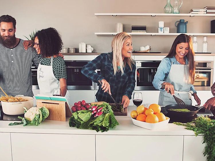 seks mennesker lager mat sammen på et stort kjøkken