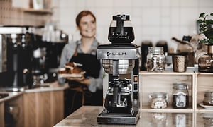 En barista står bak en CREM-kaffemaskin