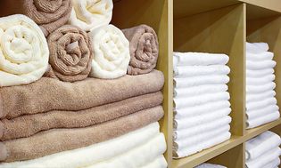 Hvite og brune håndklær brettet og stablet i en hylle