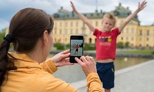 kvinne bruker en smarttelefon til å ta bilde av en gutt