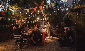 Kvinne tar et bilde av flere mennesker som sitter rundt et bord på en hagefest