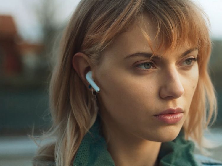 AirPods i ørene på ung kvinne som sitter utendørs
