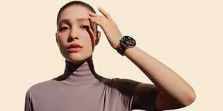 Huawei Watch 3 på armen til en kvinne foran en beige bakgrunn