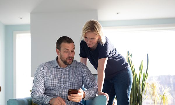 En mann og en dame som ser på en smarttelefon