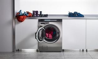 Asko Pro vaskemaskin og en benk med barneklær på