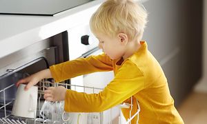 En gutt fyller oppvaskmaskinen med tallerkner