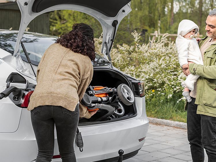 familie pakker ut fra en elbil med ladekabel tilkoblet