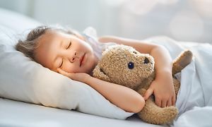 Jente sover med teddybjørnen sin 