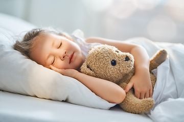 Jente sover med teddybjørnen sin 
