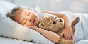 Jente sover med teddybjørnen sin 