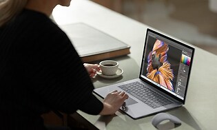 kvinne bruker en bærbar Microsoft Surface på et bord med hvit kaffekopp