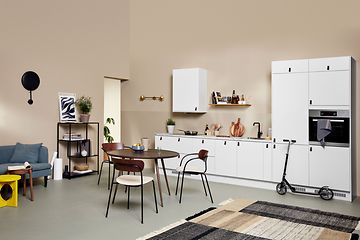 White EPOQ Core kitchen in an open kitchen solution, with couch and dining table