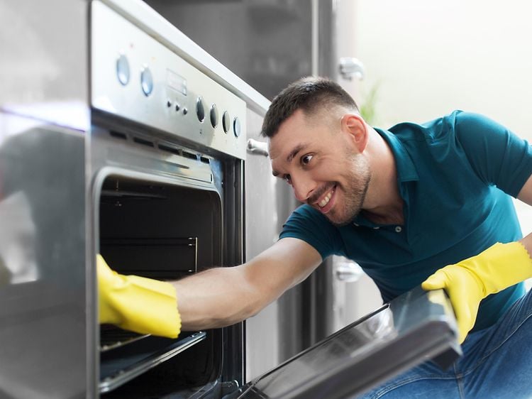 Mann som rengjør en ovn innvendig