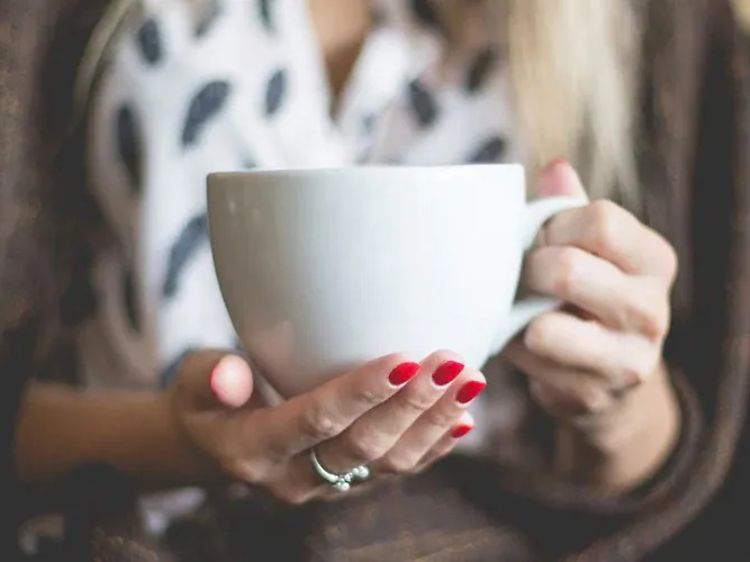 Nærbilde av kvinne som holder stor kaffekopp