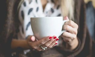 Nærbilde av kvinne som holder stor kaffekopp