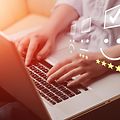 Nærbilde av hender som skriver på en laptop med vurderingssymboler oppå bildet