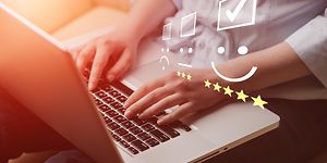 Nærbilde av hender som skriver på en laptop med vurderingssymboler oppå bildet