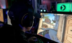 gutt med hodetelefoner sitter foran en gaming-skjerm og spiller