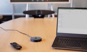 IRIS video conferance system on a meeting room table next to a laptop