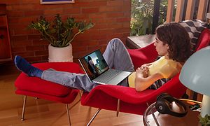 menn sitter i en rød lenestol og ser på en HP Pavilion 13