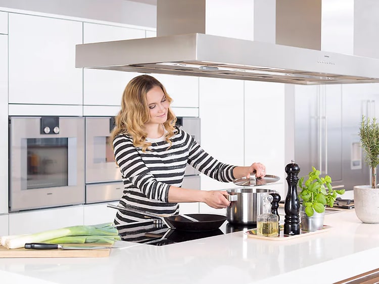  kvinne lager mat i et hvitt kjøkken
