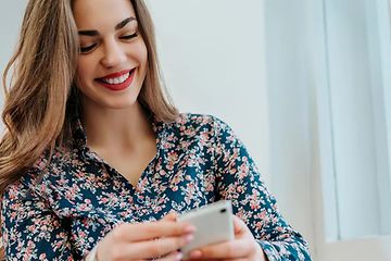 Smilende kvinne som ser på smarttelefon