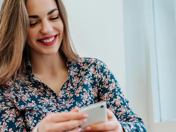 Smilende kvinne som ser på smarttelefon