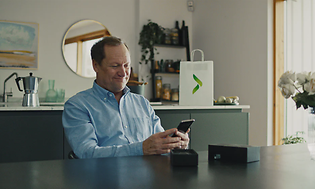 Mann sitter i stue og holder en ny iPhone