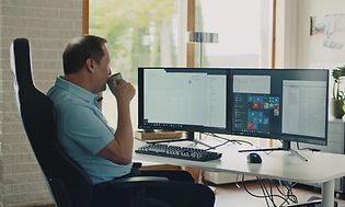 Mann sitter foran en stasjonær PC