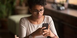 Kvinne som holder smarttelefonen og rynker på pannen
