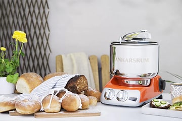 en kjøkkenmaskin fra ankarsrom på et bord med et utvalg ulike brød ved siden av