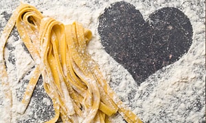 hjemmelaget pasta og mel på et bord med en form av et hjerte tegnet i melet