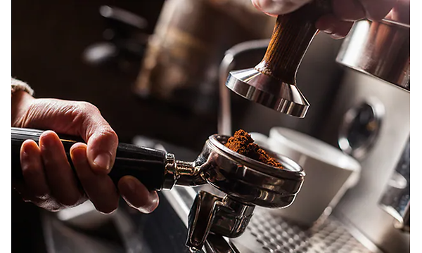 Hånd holder filterholder full av malt kaffe