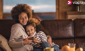 mor og datter sitter sammen i en sofa og ser på smarttelefon