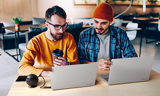 To menn sitter på en kafé og jobber med Lenovo Thinkbooks