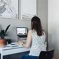 Kvinne sitter ved skrivebordet på hjemmekontoret og jobber på den bærbare datamaskinen