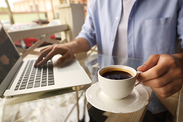 person sitter med en full kaffekopp og jobber på en bærbar pc