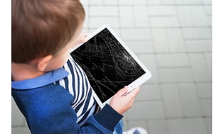 et barn holder et nettbrett med knust skjerm