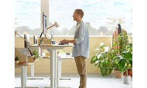 mann står ved skrivebord og bruker et ergonomisk tastatur