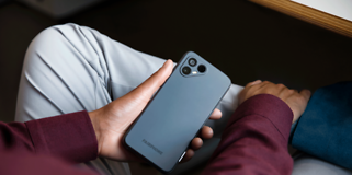 Fairphone 4 i hånden på en som sitter innendørs
