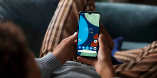 Fairphone 4 i hånden til en person som ligger og slapper av