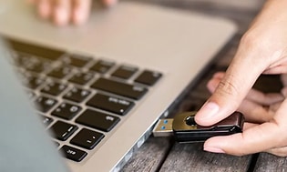 en person plugger en USB minnepinne inn i en macbook