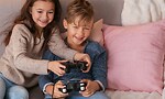 To barn som spiller TV-spill sammen i en sofa